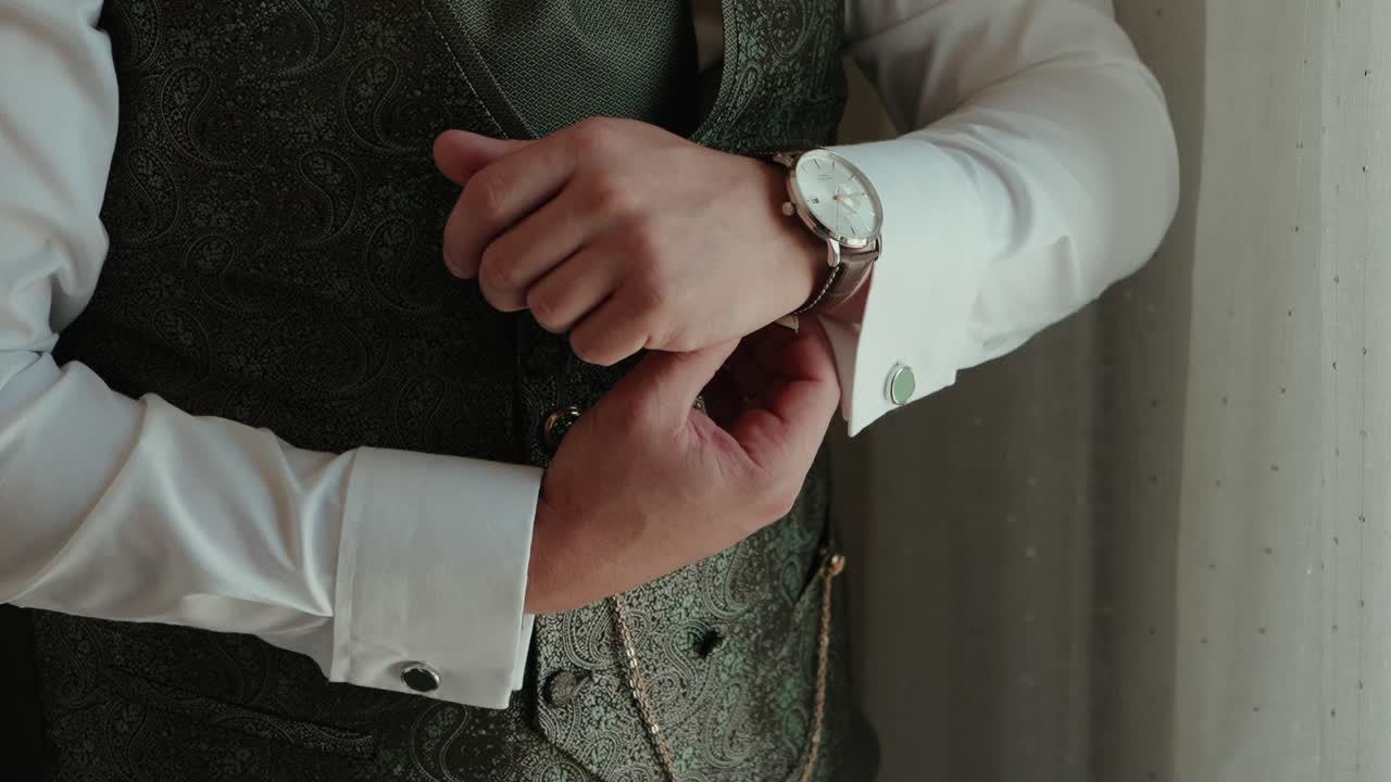 Closeup of groom adjusting wristwatch in classic wedding suit