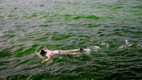 A-young-tourist-woman-diving-in-the-sea-near-de-surface-in-the-area-of-Bombas-and-Bombinhas-beaches,-Brazil