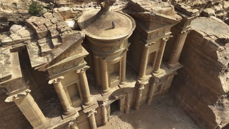 arab on top of the famous el-deir monastery, in sunny jordan - aerial tilt reveal