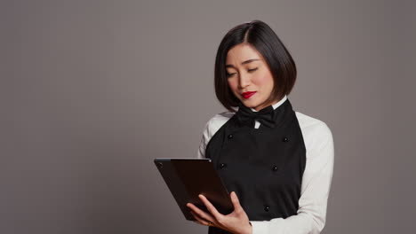 asian restaurant server checking all table reservations on tablet