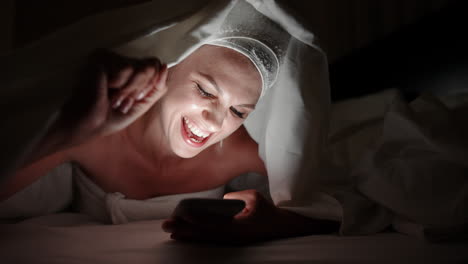 woman using phone in bed at night