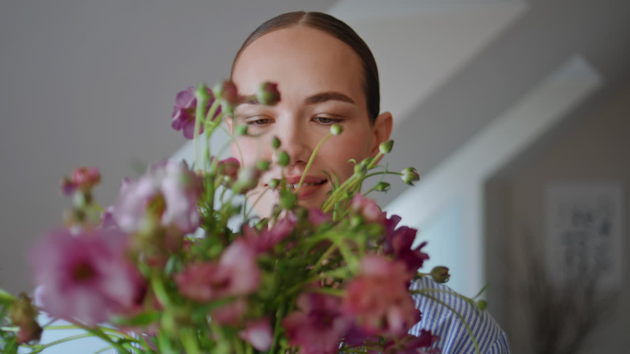 Portrait woman embracing flowers in cozy apartment. Happy girl sniffing aroma