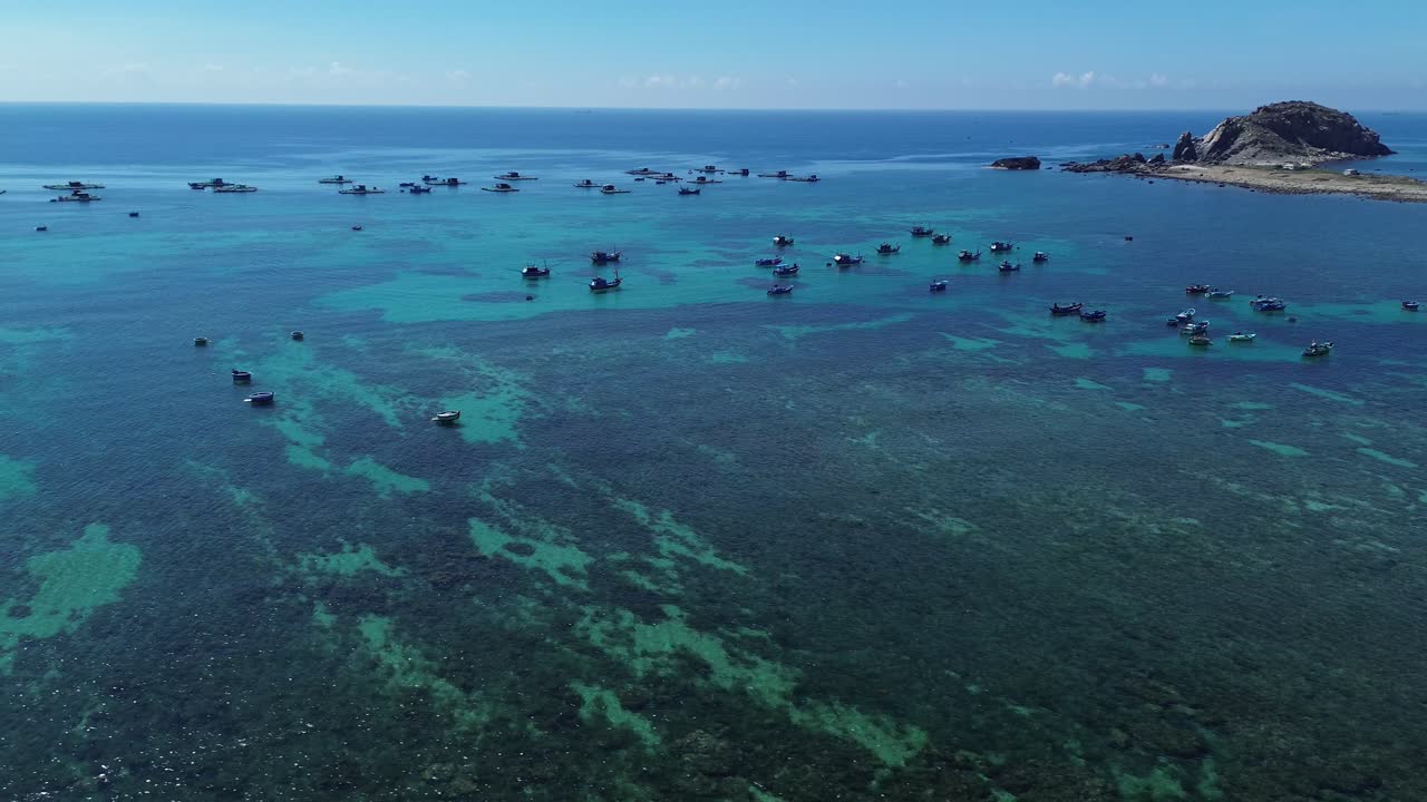 Pan left aerial shot showing traditional fishing boats over clear waters at Phan Rang in Ninh Hải District, Ninh Thuận, Vietnam