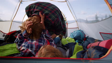 playful man and woman cuddling in camping tent