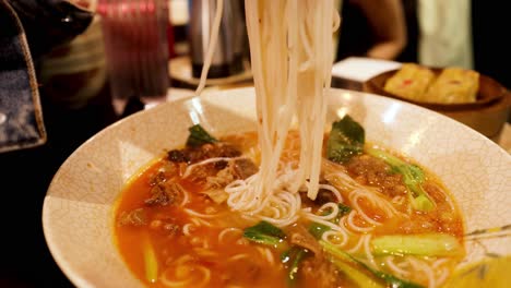 noodles lifted from bowl with chopsticks