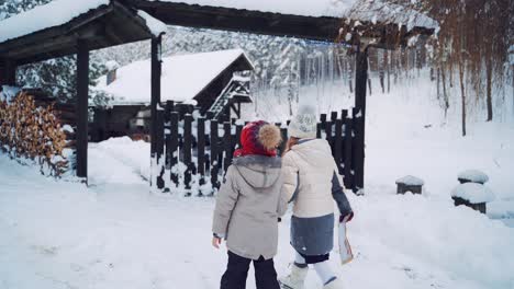 small children coming to the wooden gate in winter. back view of curious kids looking on the big christmas envelope on the background of house in forest in winter.