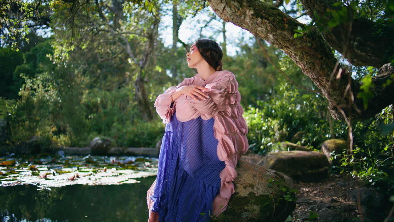 niña posando en un bosque encantado, un lago, un día de verano. mujer romántica sentada bajo un árbol.