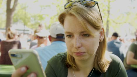 Mujer-Está-Mirando-Su-Teléfono-Inteligente-En-Un-Lugar-Lleno-De-Gente