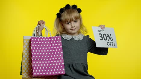 Child-girl-showing-Up-To-30-percent-Off-inscription-sign-and-shopping-bags.-Teen-pupil-smiling