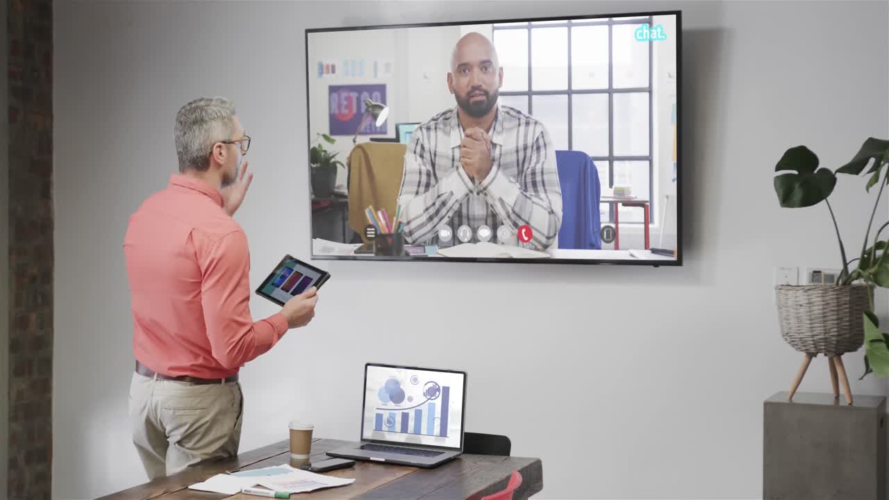 Caucasian businessman on video call with african american male colleague on tv screen
