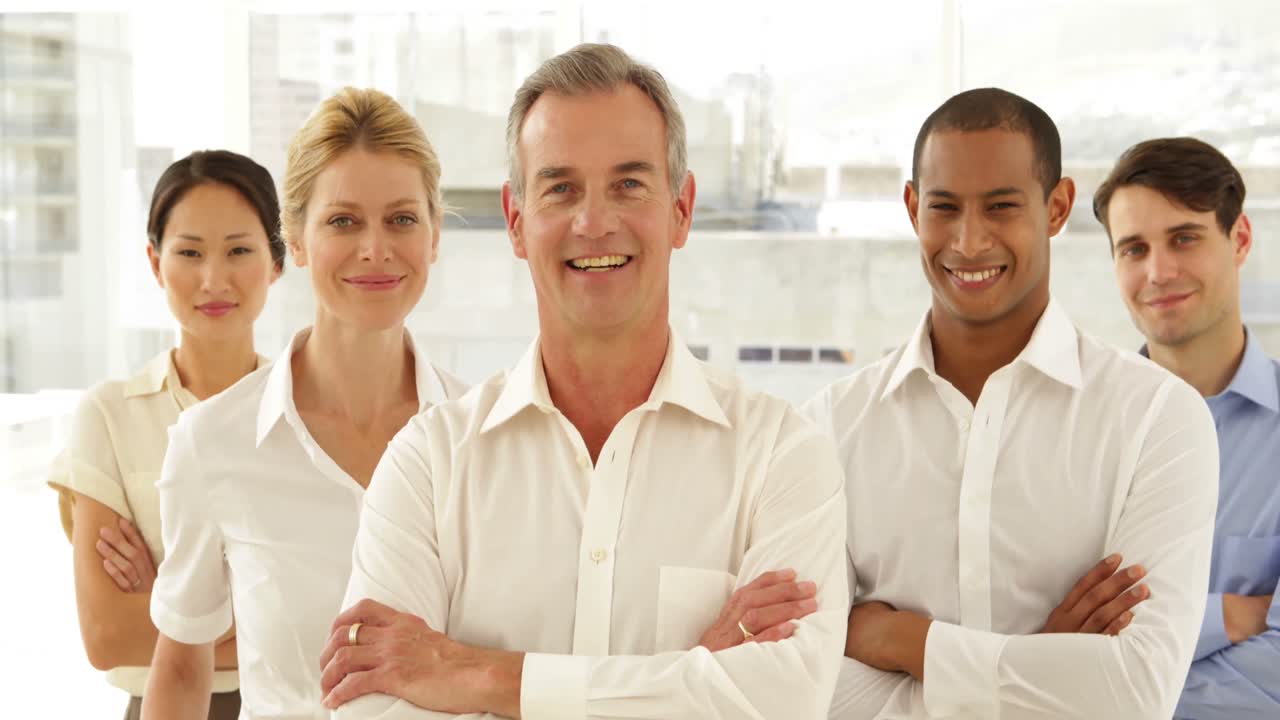 hombre de negocios sonriendo a la cámara con el personal detrás de él