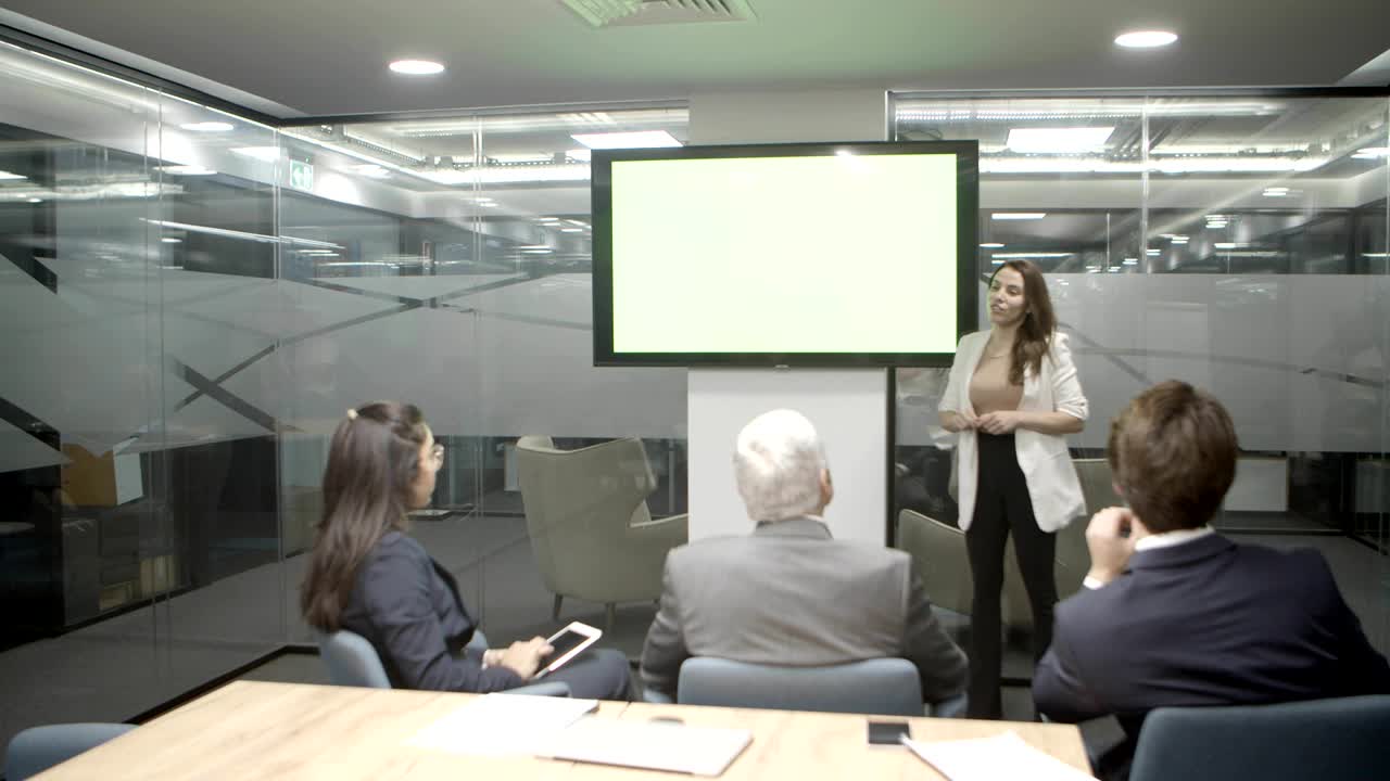 oradora enfocada hablando mientras está de pie cerca de la pantalla