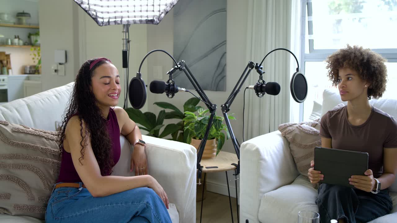 Presentadoras afroamericanas grabando podcast en casa, con anillo de luz LED encendido, usando micrófonos de brazo