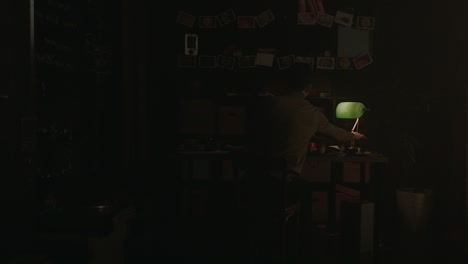 persona sentada en un escritorio oscuro en una habitación
