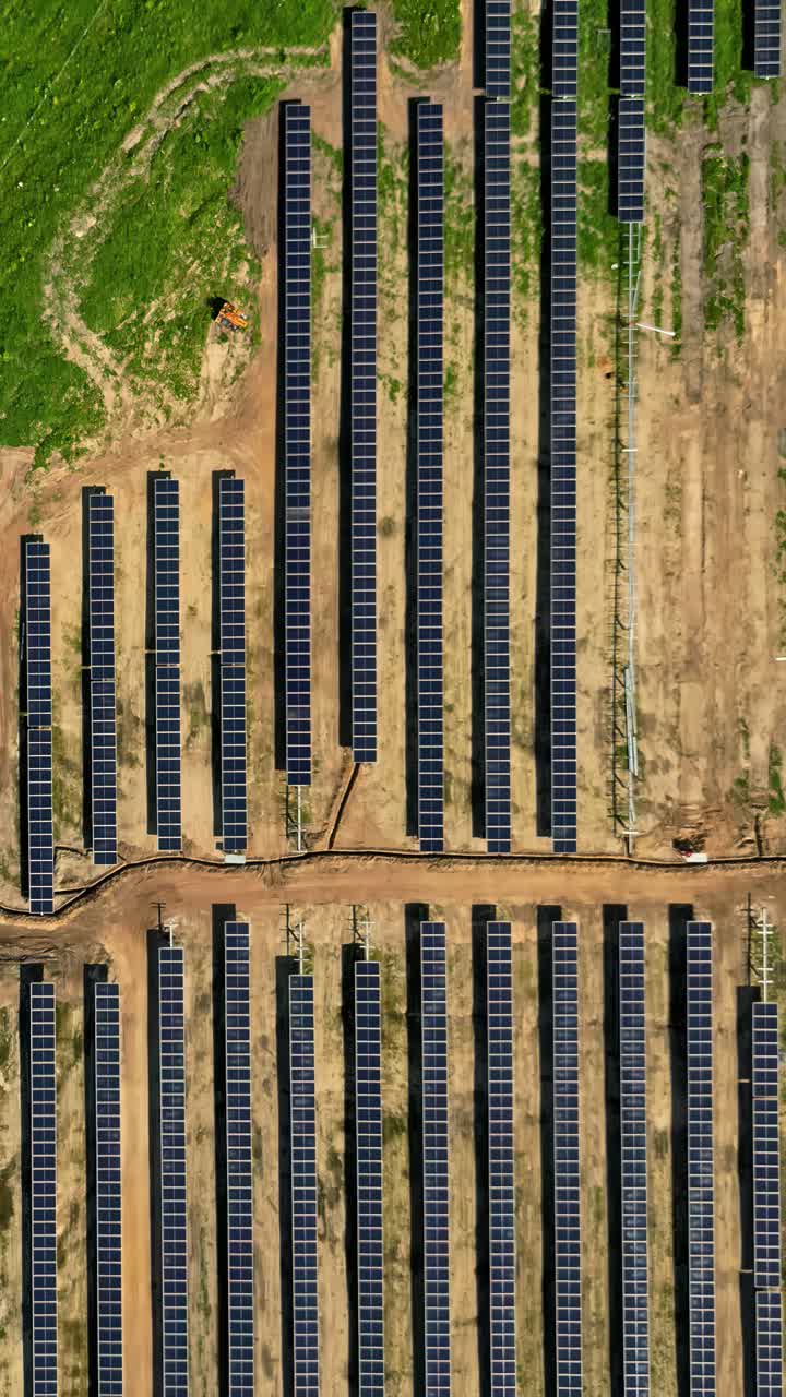 Vertical aerial view of many solar panels arranged on the ground of a farm