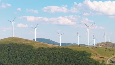 beautiful drone footage of green energy turbines rotating on mountain slopes with blue sky and drifting clouds. clean energy in scenic nature