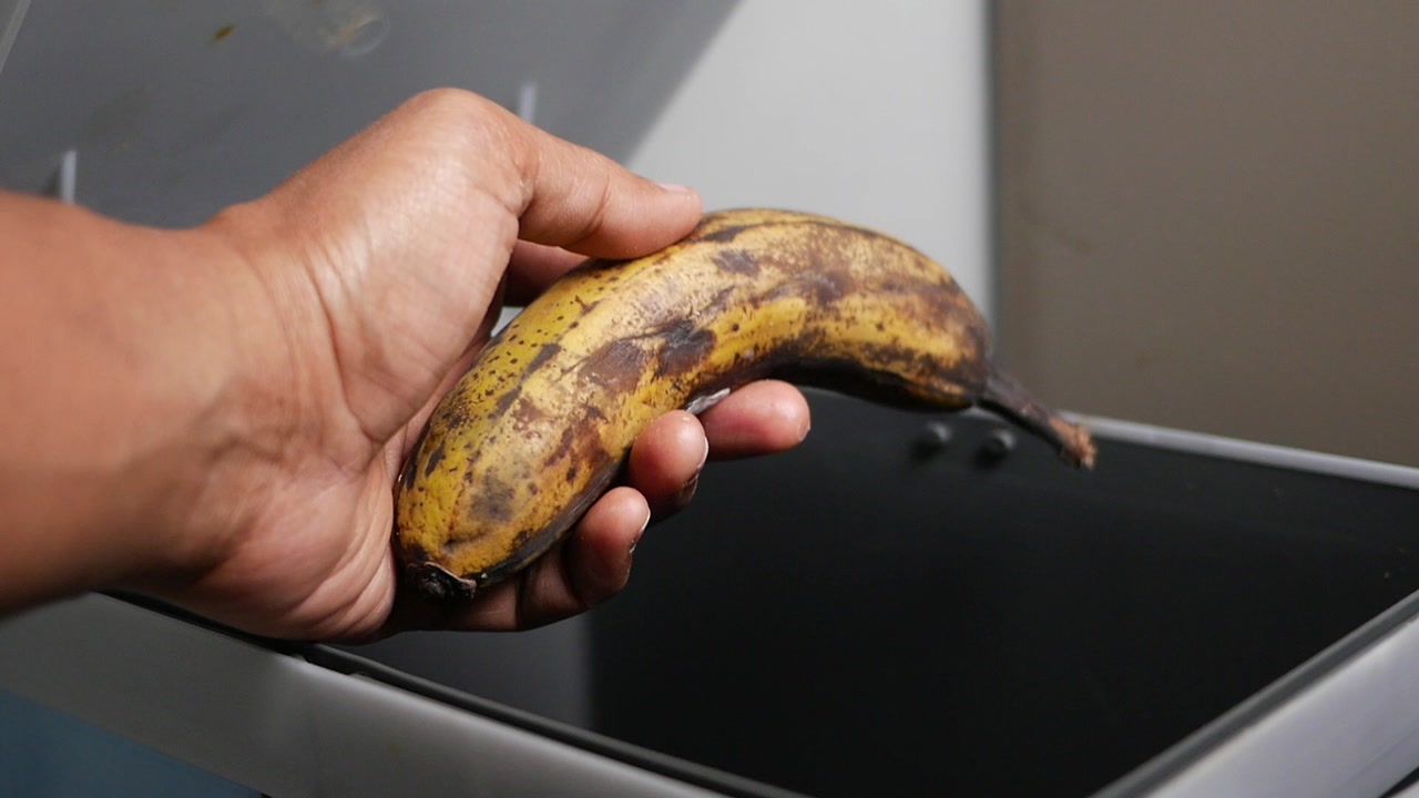 Close-up of Hand Discarding a Rotten Banana into a Waste Bin