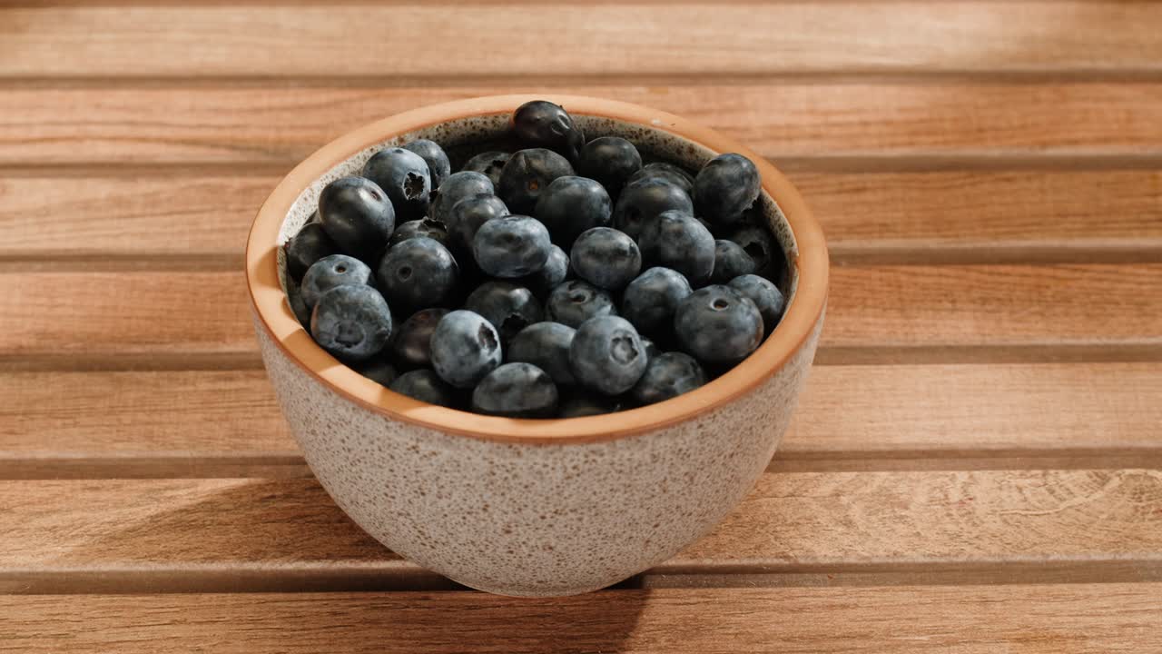 나무 테이블 위 에 블루베리 가 있는 그 을 들고 있는 여자