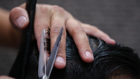 close-up of a barber cutting a man's hair with comb and scissors