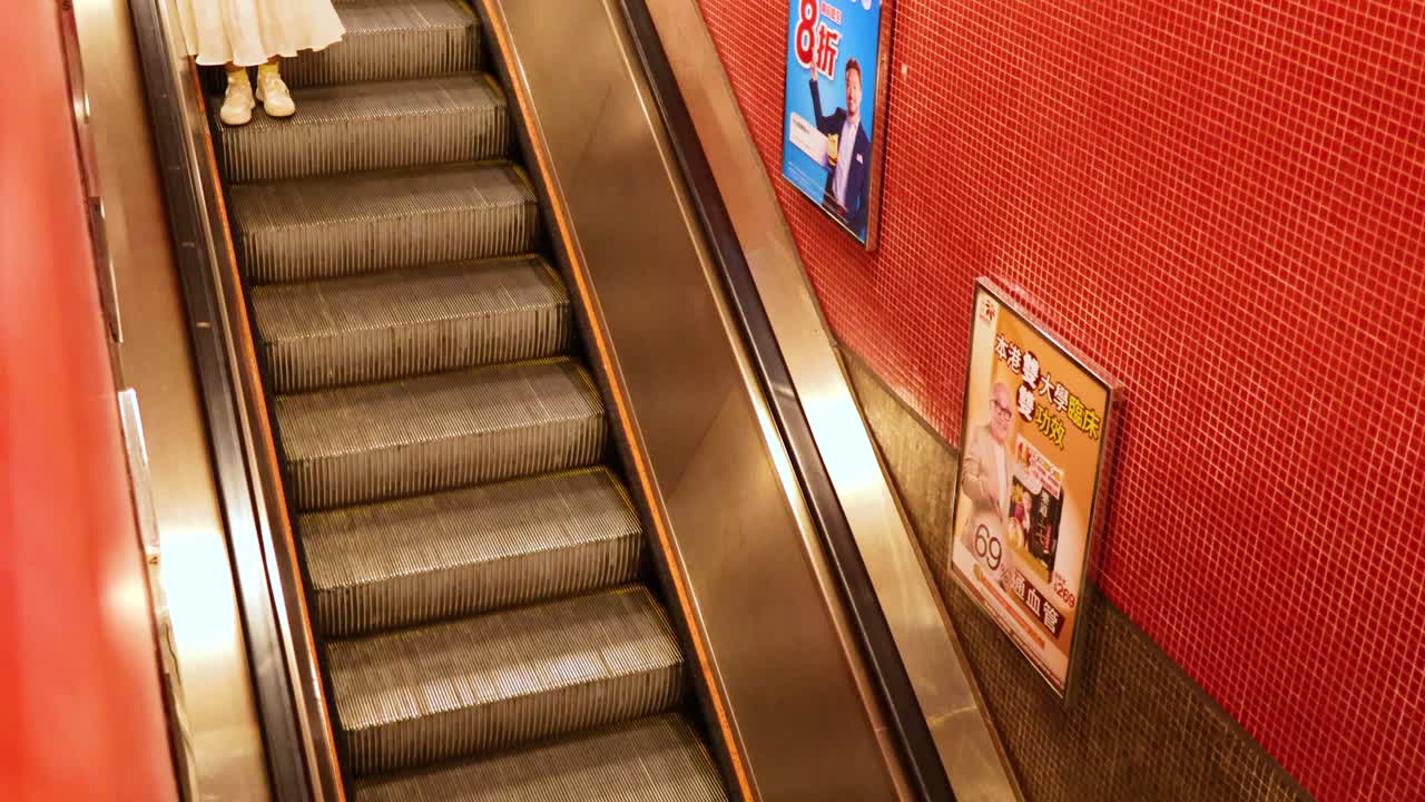 gente usando una escalera mecánica en una estación de metro en hong kong.