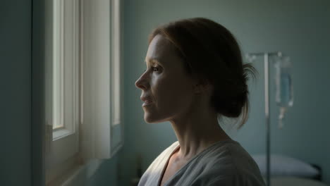 woman looking out a window in a hospital room