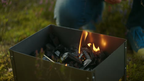 hiker is resting in camping preparing coals in chargrill for cooking slow motion shot of man and flames