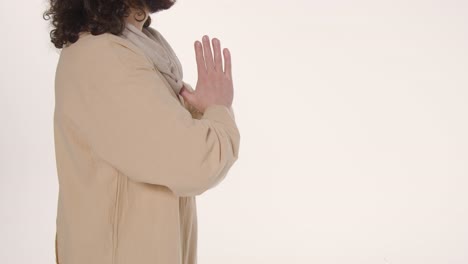 close up shot of man wearing robes with long hair and beard representing figure of jesus christ praying 3