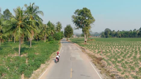 Mujer-Monta-Motocicleta-A-Lo-Largo-De-La-Carretera-Asfaltada-Vista-Trasera