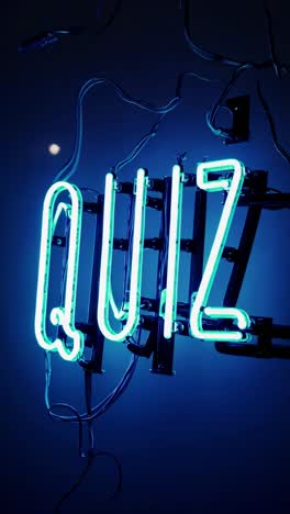 turquoise neon sign glowing with the word quiz illuminates a dark blue room, featuring visible electrical wires and hanging gracefully from the ceiling, creating a vibrant atmosphere