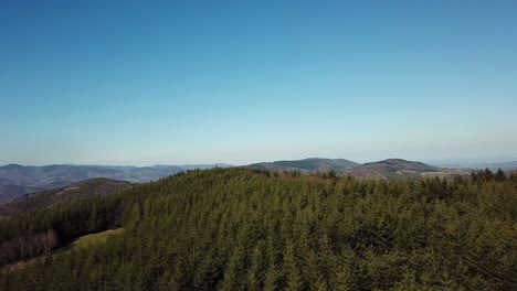 rising drone shot of a forest with hills to the horizon in ardèche, france