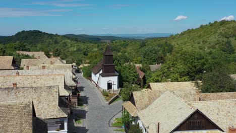 Drone-flies-over-the-historical-streets-of-Holloko,-Hungary-in-the-afternoon