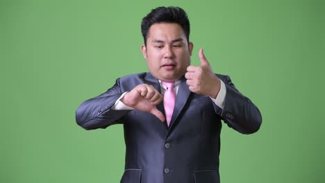 young handsome overweight asian businessman against green background