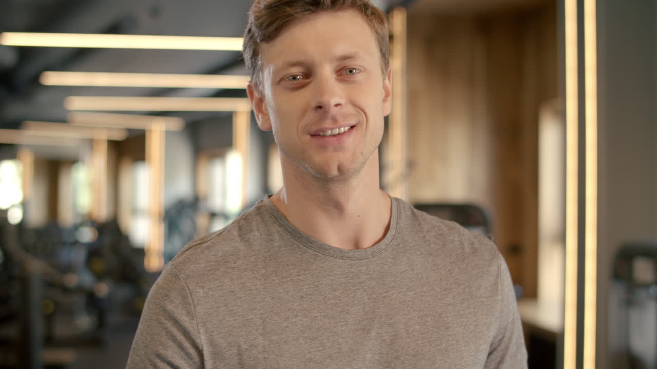 Smiling fitness man showing ok sign in sport club. Sportsman standing at gym.