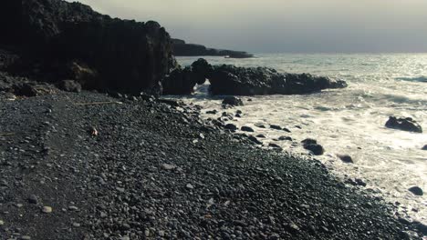 Low-forward-aerial-along-shore-by-Manawainui-Gulch-View-Sea-Cave,-Maui