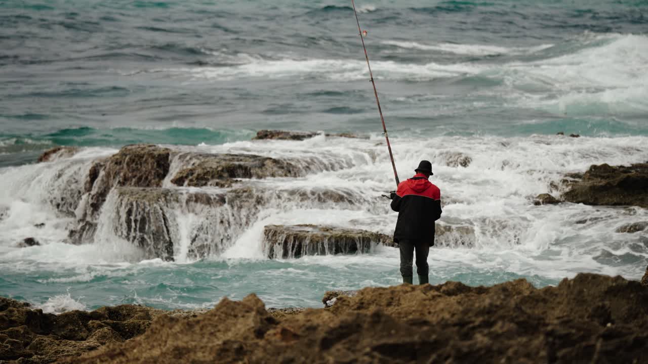 Seorang nelayan berdiri di pantai berbatu Tangier, melemparkan pancing ke perairan Atlantik yang berombak