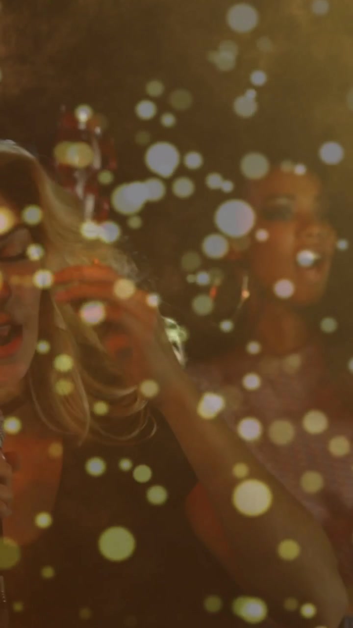 Vertikal video: Musikalsk indledning med kvindelig forsanger, der holder mikrofon og synger, med varm bokeh-effekt for publikum.