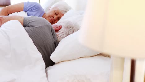 Senior-couple-sleeping-on-bed-in-bedroom