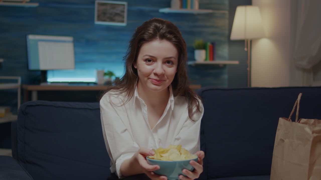 Caucasian adult looking at camera while having bowl of chips