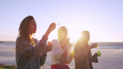 girl friends blowing bubbles on beach at sunset slow motion