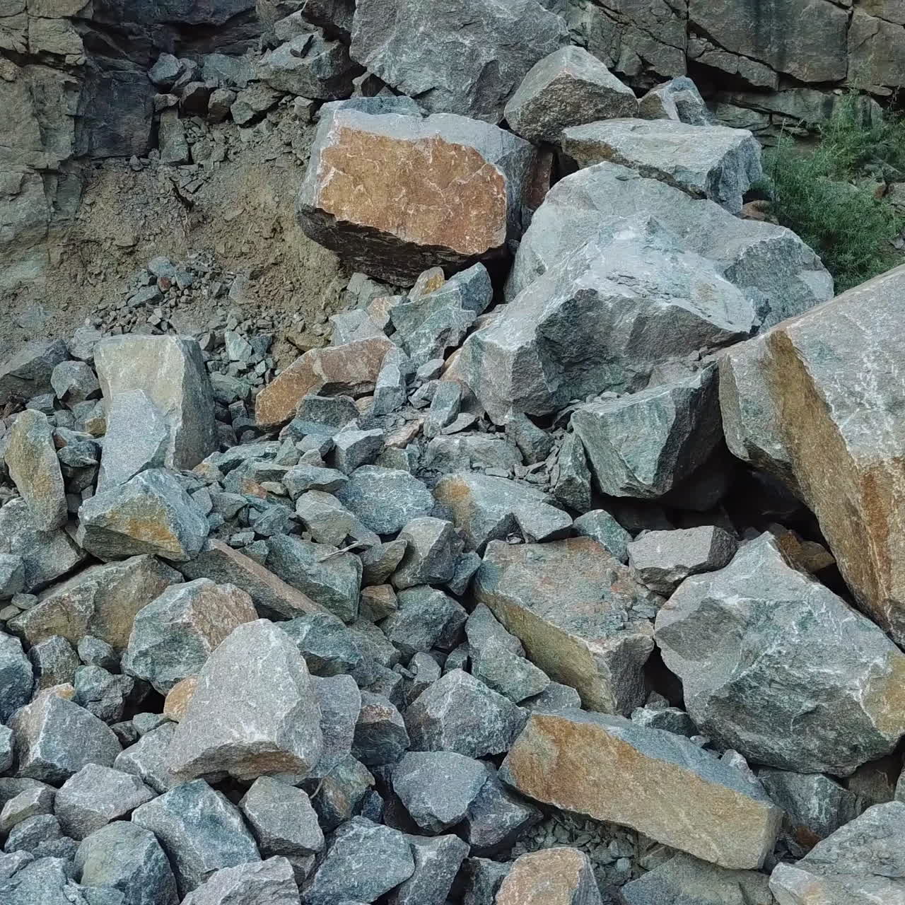A man in a black t-shirt and a backpack comes to the edge of a large stone and raises his hands up. Tourist got to the center of stone quarry.