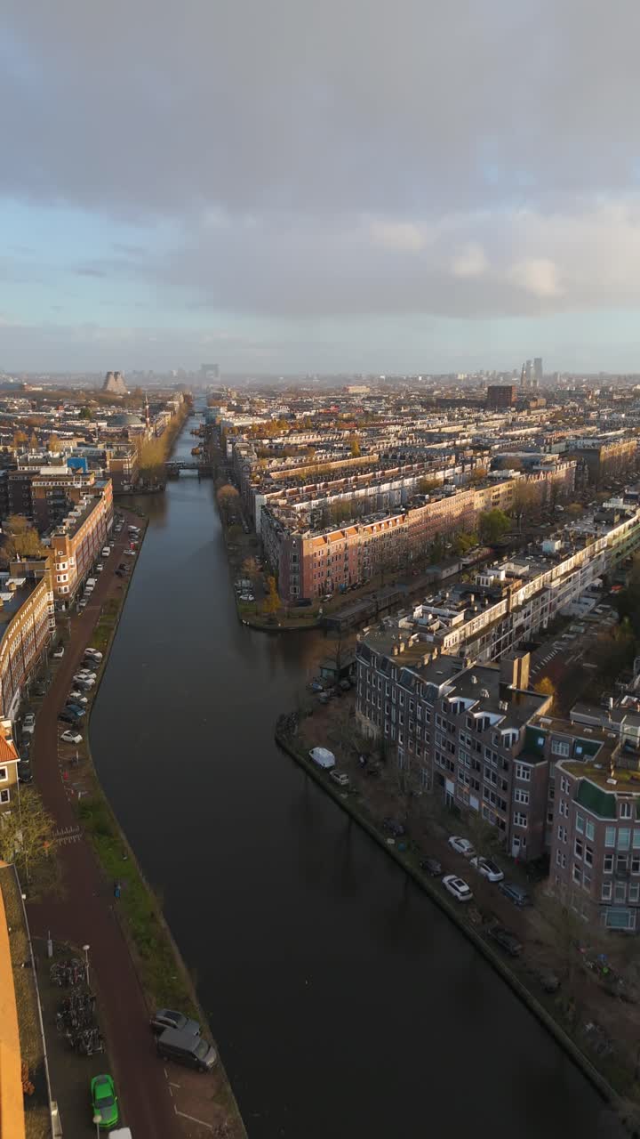 Vertical drone shot over a canal in Amsterdam city, fall sunset in Netherlands