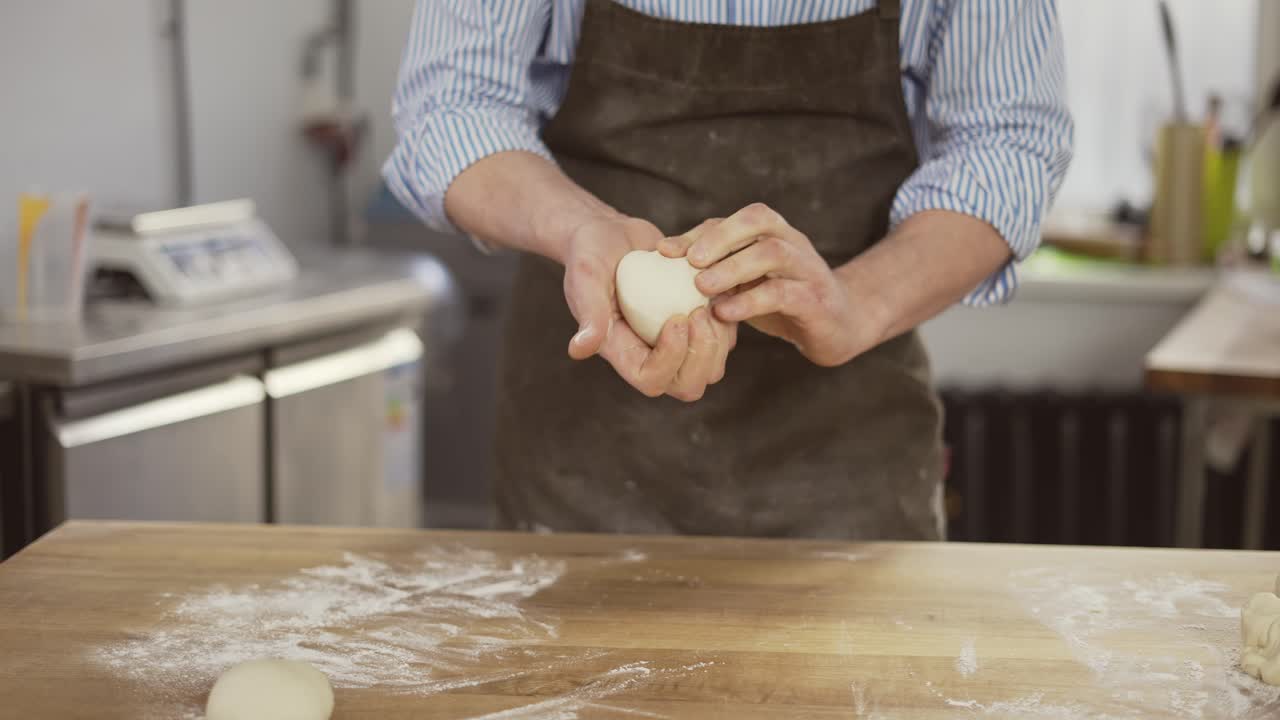 Baker kneads dough and making bread. Chef prepares dough with flour. Hands kneading the dough on table. Baker hands close up. Preparing bread. Male hands close-up