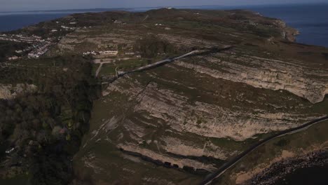 Aerial-drone-flight-over-The-Great-Orme-in-Llandudno-Wales-showing-the-rocky-cliffs-and-ocean-in-the-distance