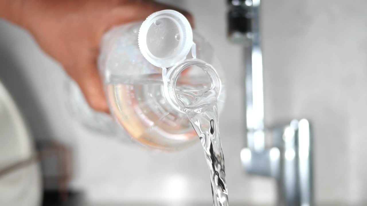 vertiendo agua de una botella en un fregadero