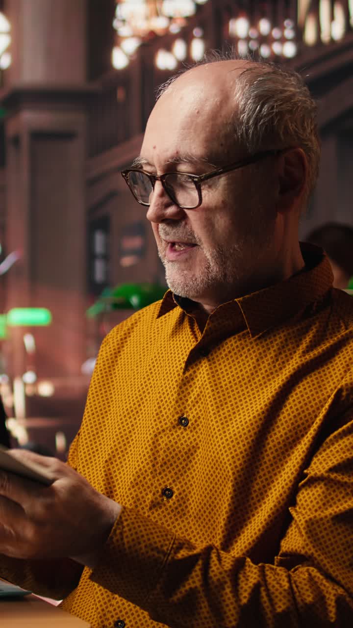 Vertical Video Wise aged person reading a book at the public library and enjoying free time