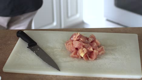 cubing chicken on white cutting board