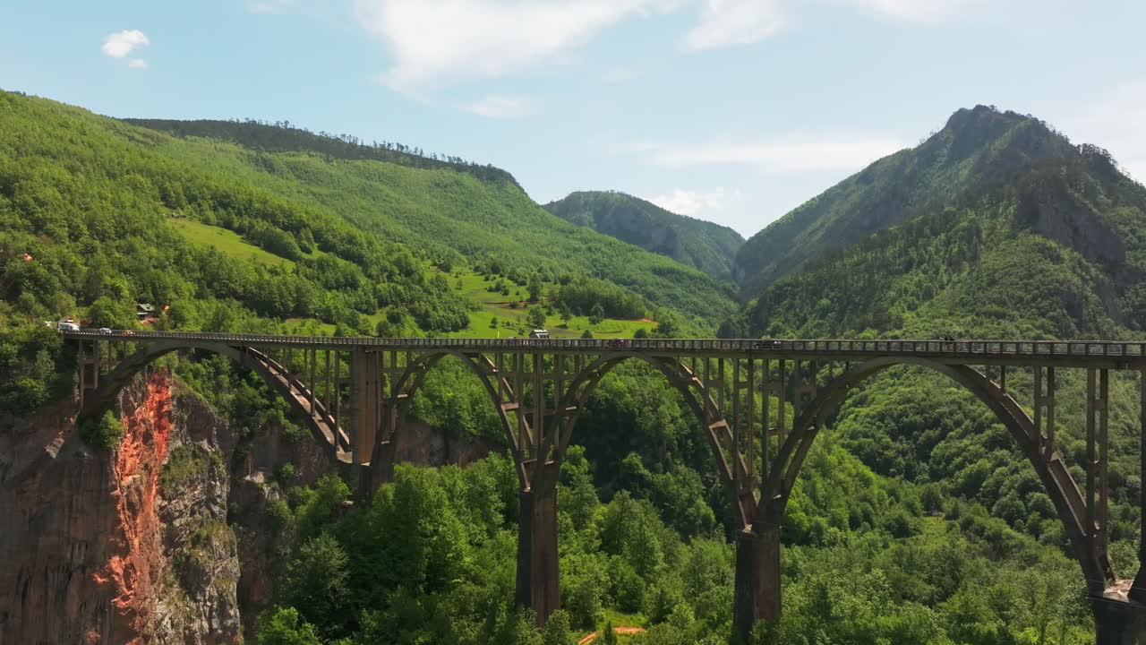 Drone flight along traffic on Tara UNESCO Montenegro bridge in lush wilderness