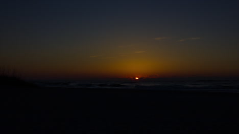 stunning sunrise timelapse. misty vibrant colourful cloudy sky, lens flare, large island visible on the far horizon of the sea.