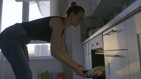 mujer sacando un plato asado del horno