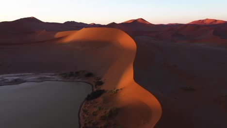 flying over a oasis and sand dunes, sunset in the namib desert of namibia - aerial view